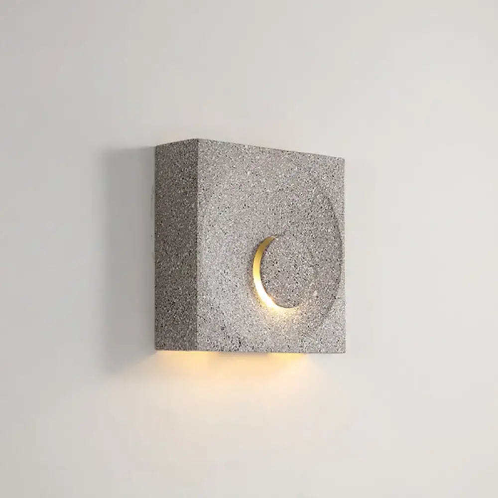Modern black and gold cement square wall light with gray textured concrete sconce and warm glowing crescent light type