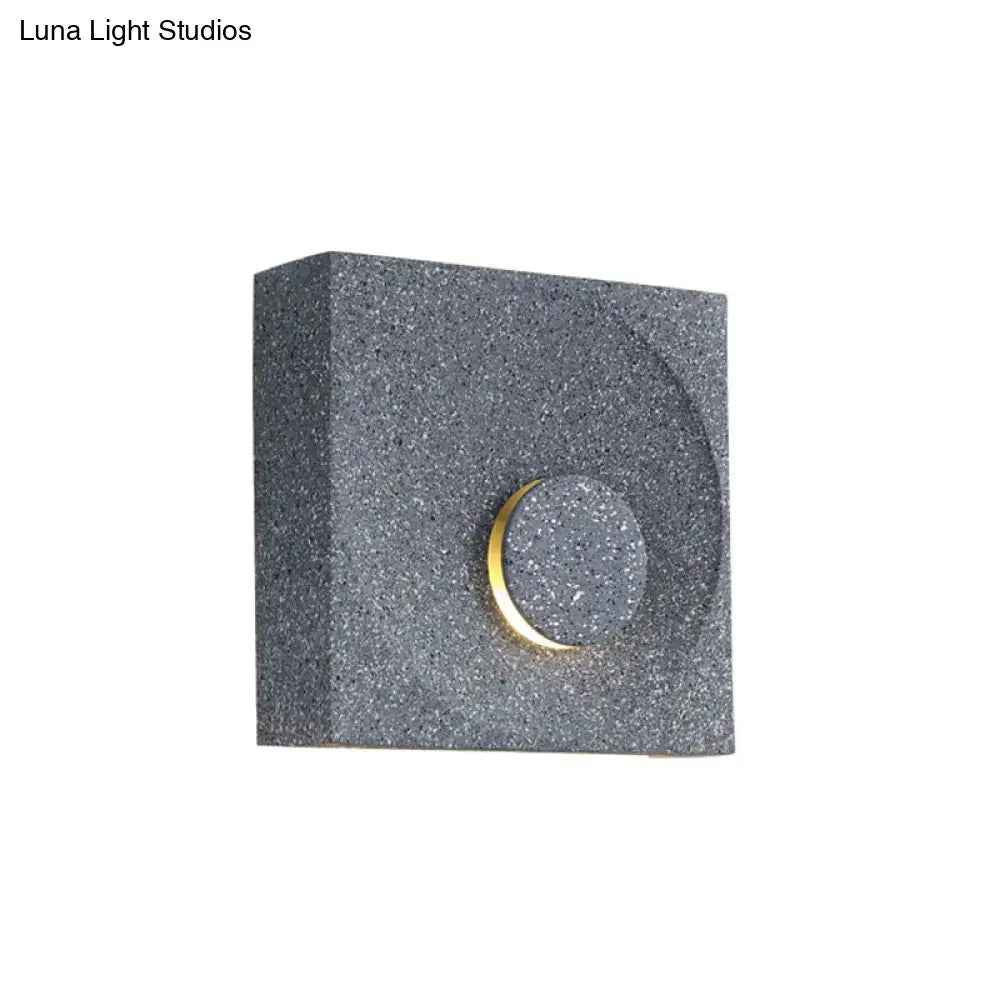 Modern black and gold cement square wall light with gray speckled finish and circular accent for bedroom use