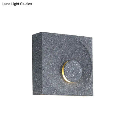 Modern black and gold cement square wall light with gray speckled finish and circular accent for bedroom use