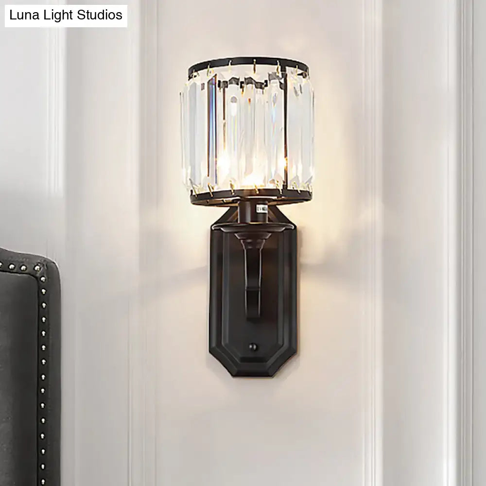 Modern black gold wall sconce with clear crystal cylindrical shade and fixture height ideal for bedroom lighting
