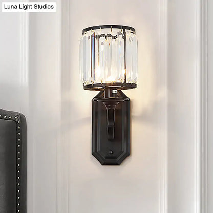 Modern black gold wall sconce with clear crystal cylindrical shade and fixture height ideal for bedroom lighting