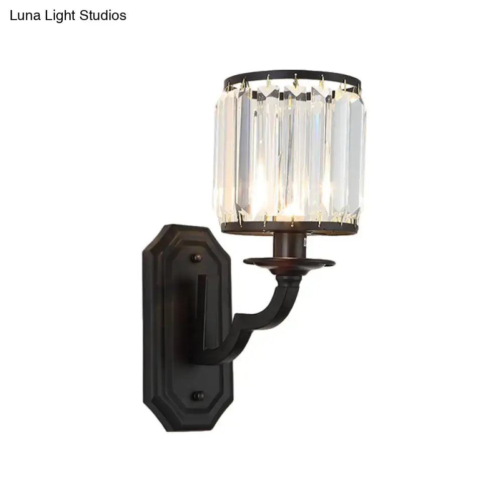 Modern black gold wall sconce with clear crystal prisms and cylindrical glass shade highlighting fixture height