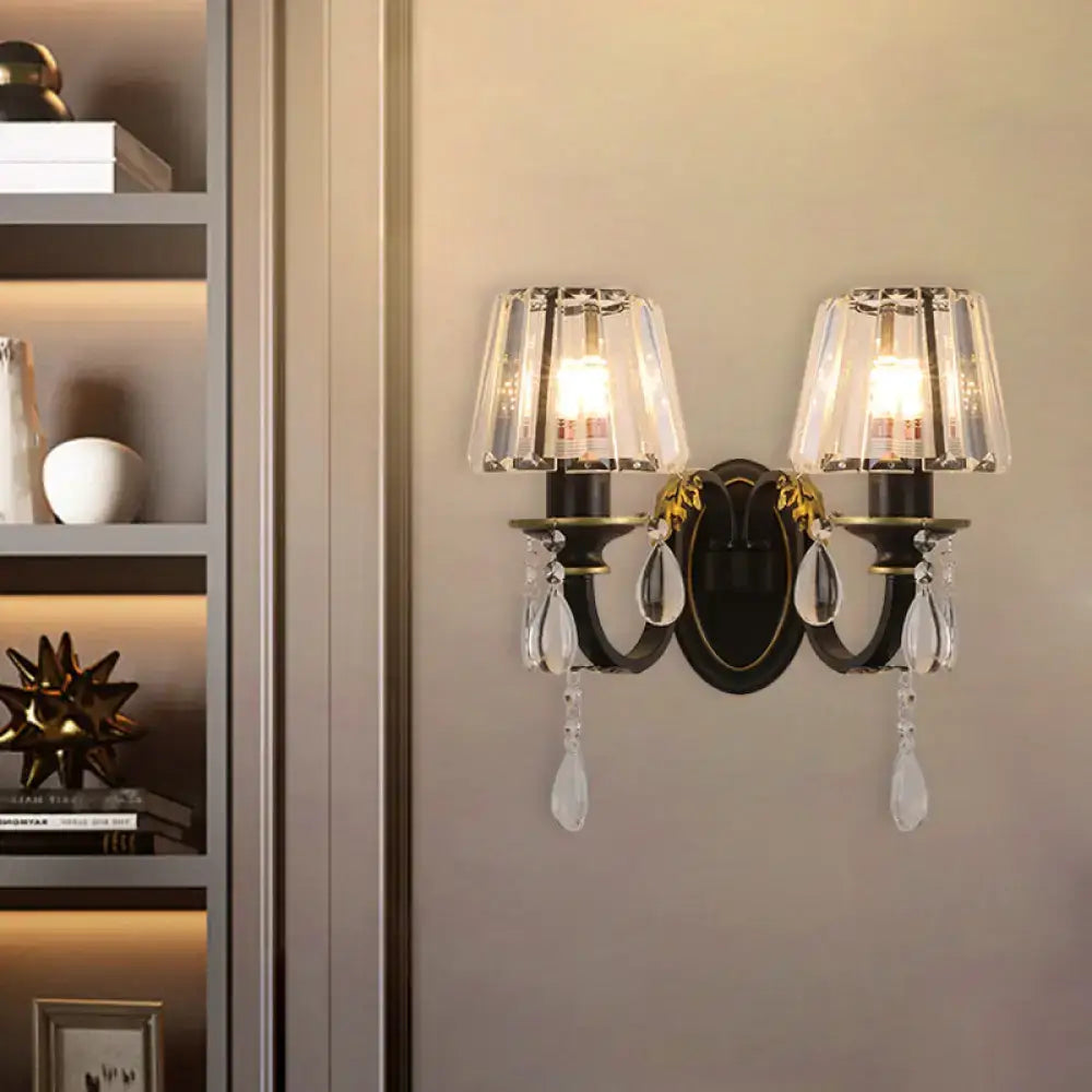 Modern black and gold ornate wall lamp with conical crystal shades and dangling teardrop crystals for living room use