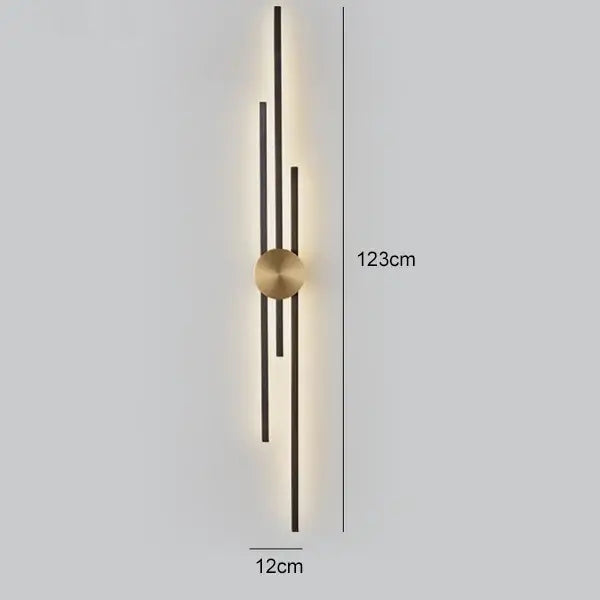 Modern black and gold copper wall light with a brass circular base and five black rods illuminated by warm led lighting