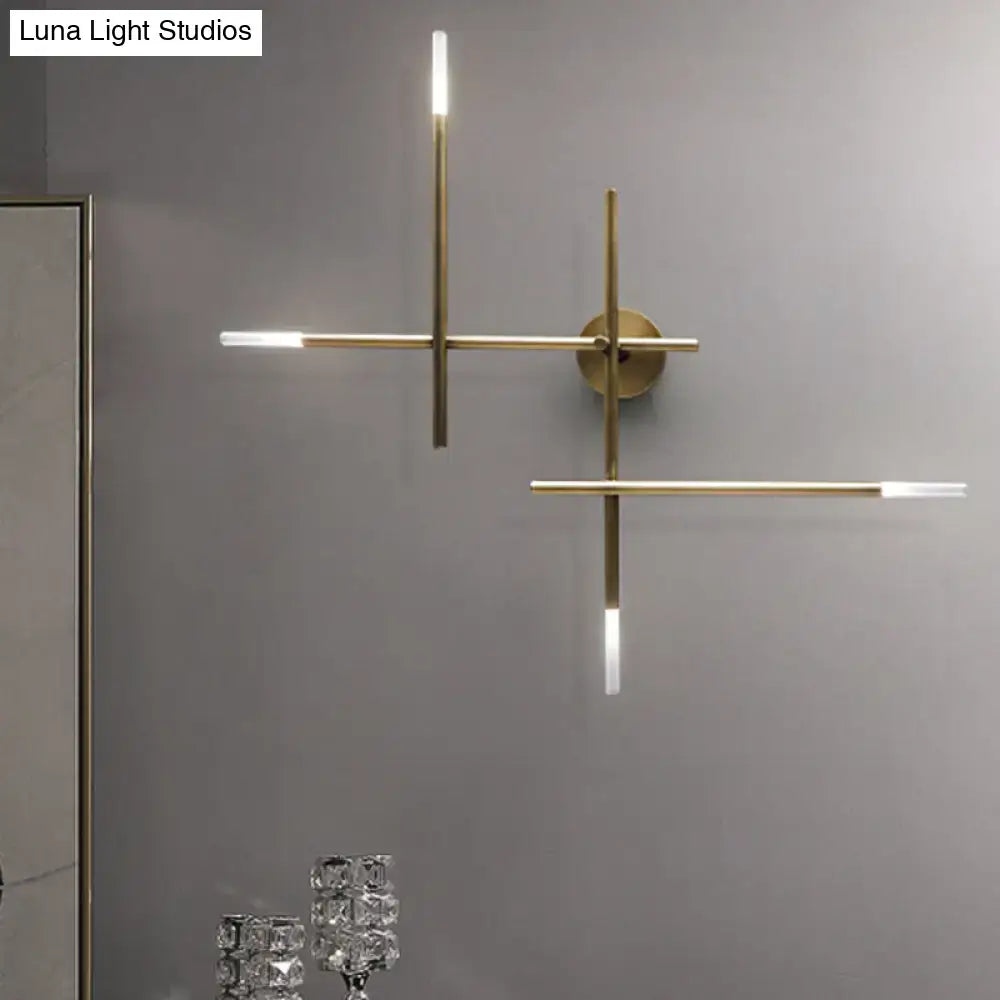 Modern gold-toned wall light featuring minimalist crossed lines and integrated led light fixture for bedroom use