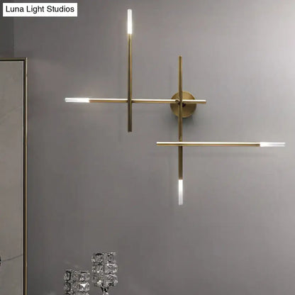 Modern gold-toned wall light featuring minimalist crossed lines and integrated led light fixture for bedroom use