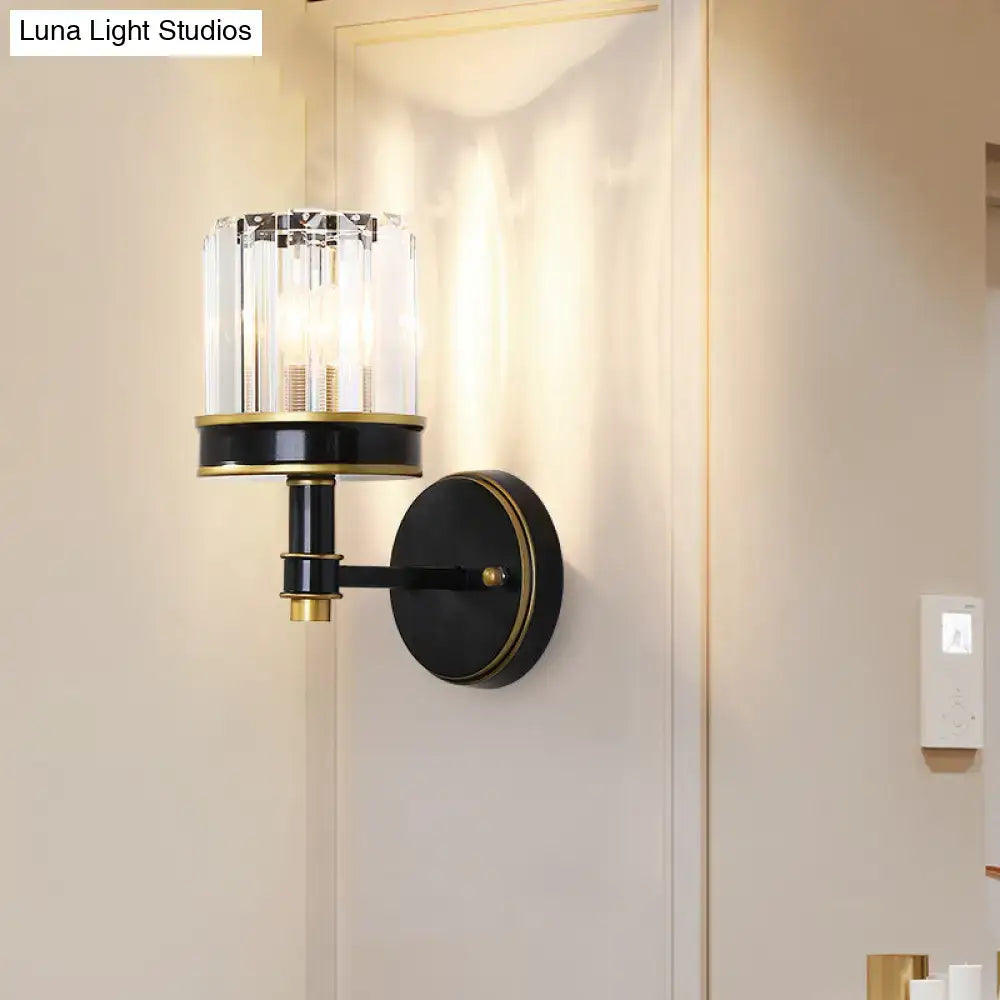 Modern black and gold wall light with crystal cylinder housing three candle-style bulbs for hallway use