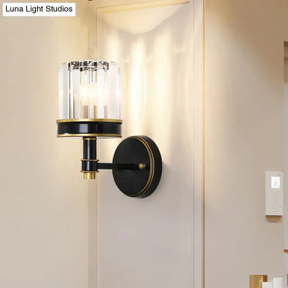 Modern black and gold wall light with crystal cylinder housing three candle-style bulbs for hallway use