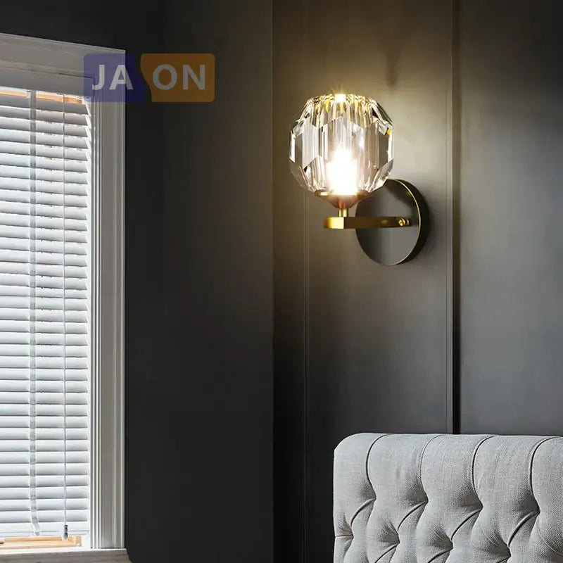 Modern black and gold decorbites crystal led wall sconce featuring a faceted crystal globe and metal base for bedroom light