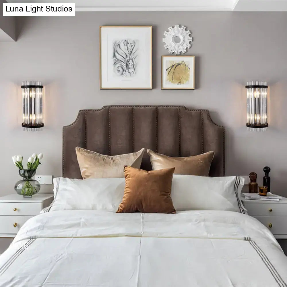 Brown tufted velvet headboard with nailhead trim paired with modern black and gold crystal rod cylinder wall sconce for bedroom lighting