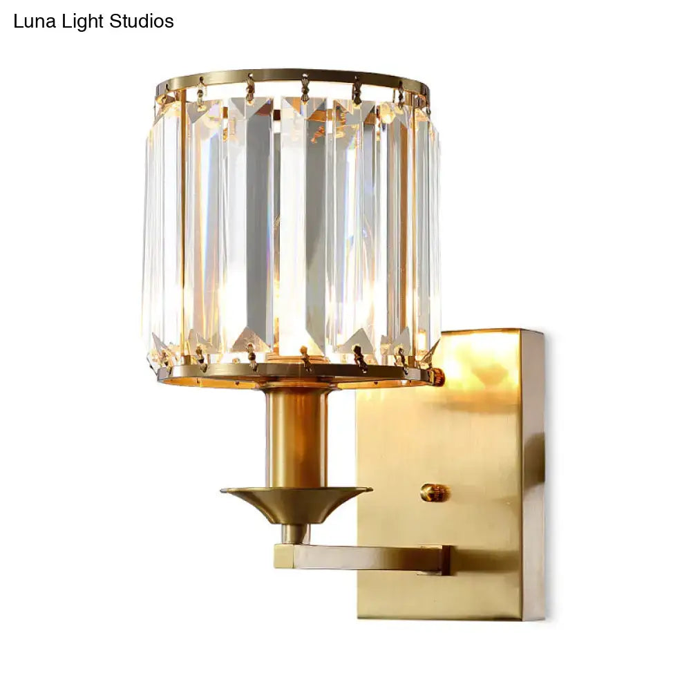 Modern black and gold sconce light fixture with direct wired electric power featuring a gold-toned crystal cylindrical shade