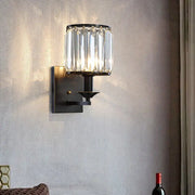 Modern black and gold sconce light fixture with cylindrical crystal shade for wired electric power bedroom use