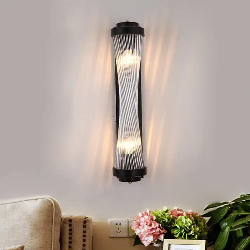 Modern black and gold crystal wall lamp with ribbed glass panels emitting warm light for bedroom and living room
