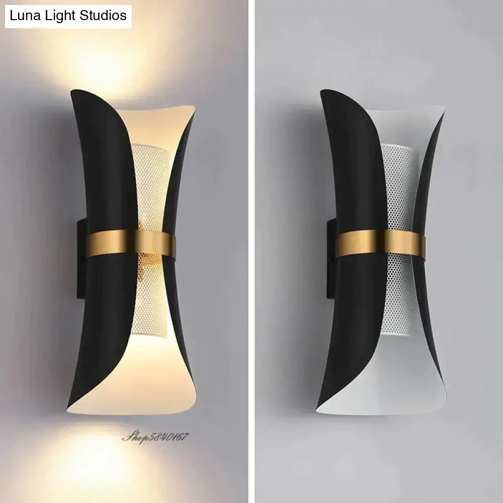 Modern black and gold curved wall lamp featuring a sculptural design with a perforated mesh panel for bedroom use