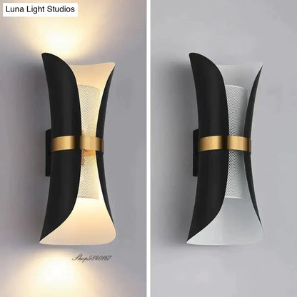Modern black and gold curved wall lamp featuring a sculptural design with a perforated mesh panel for bedroom use