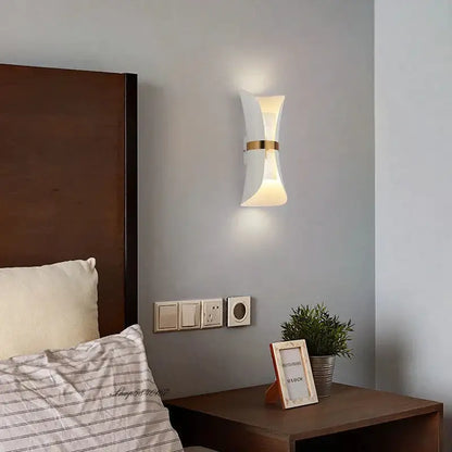 Modern black and gold curved wall lamp with white sculpted wall sconce and gold accent band for bedroom lighting