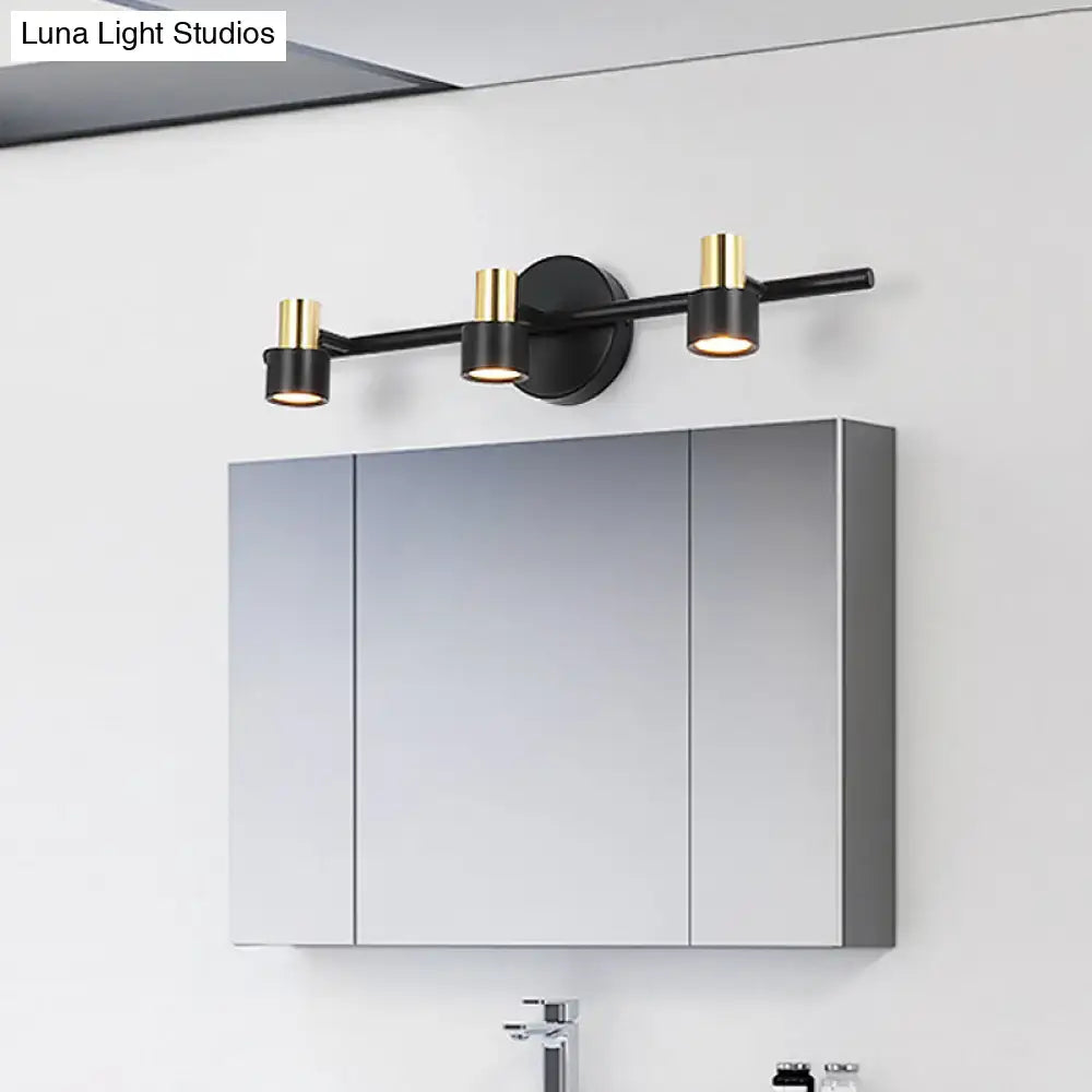 Modern black and gold cylinder wall light with three sleek cylindrical shades for bathroom vanity illumination
