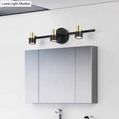 Modern black and gold cylinder wall light with three sleek cylindrical shades for bathroom vanity illumination