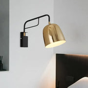 A sleek modern black and gold dome wall sconce with a polished brass dome shade and curved arm for bedroom lighting 220v-240v