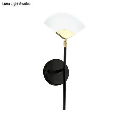 Modern black and gold wall mount light featuring a sleek brass design with a frosted glass shade for bedroom use