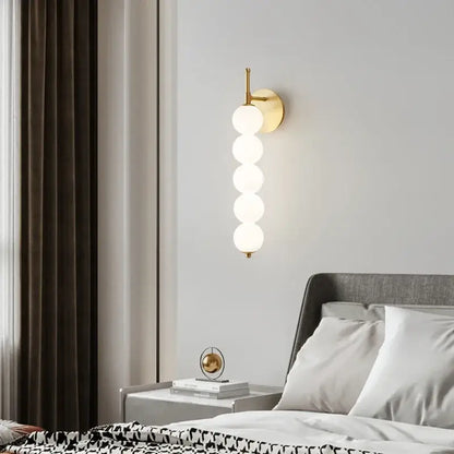 Modern black and gold glass bedside led wall lamp with gold-toned wall sconce and five stacked frosted glass spheres