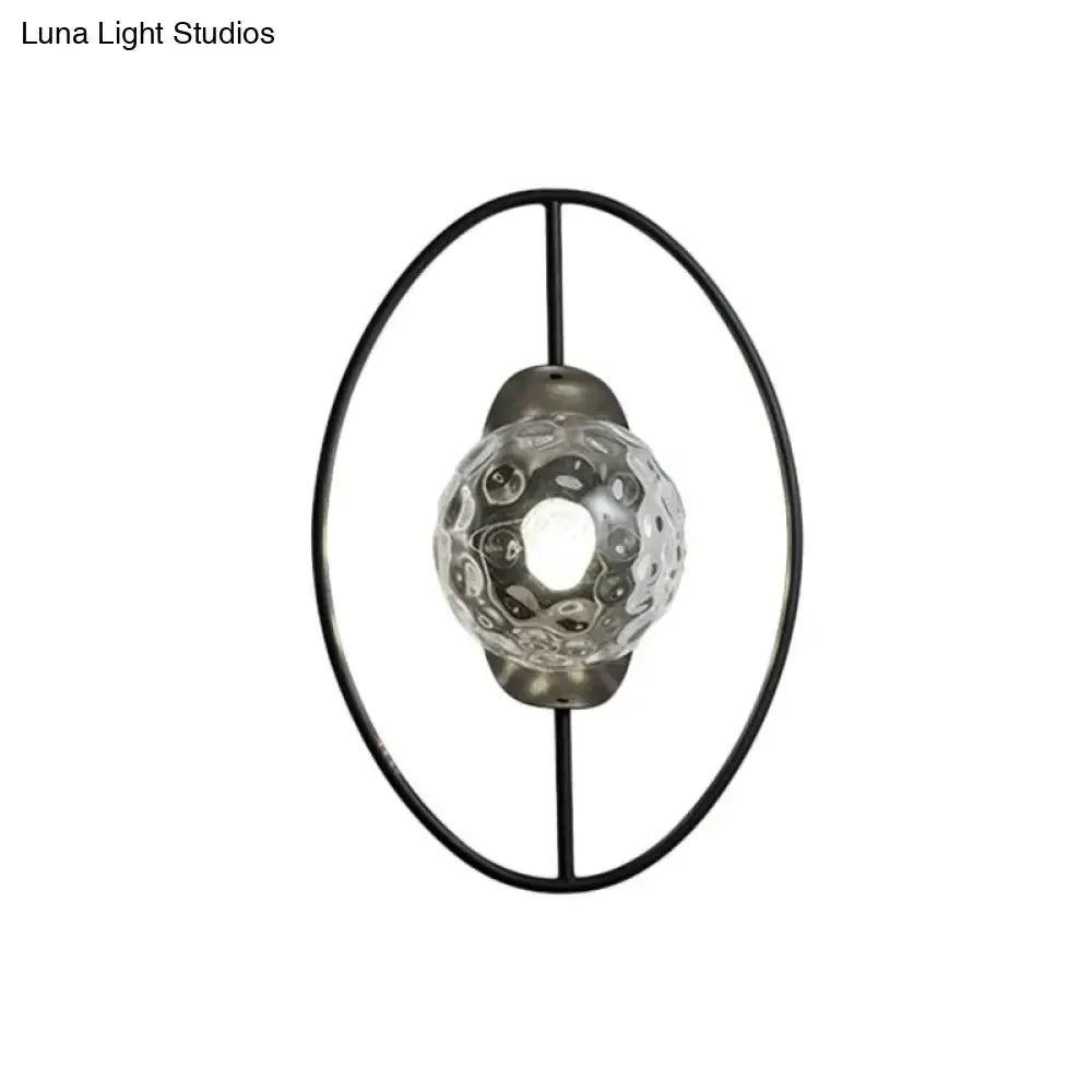 Modern black and gold wall lamp with black metal oval frame and clear textured glass orb fixture type for bedroom use