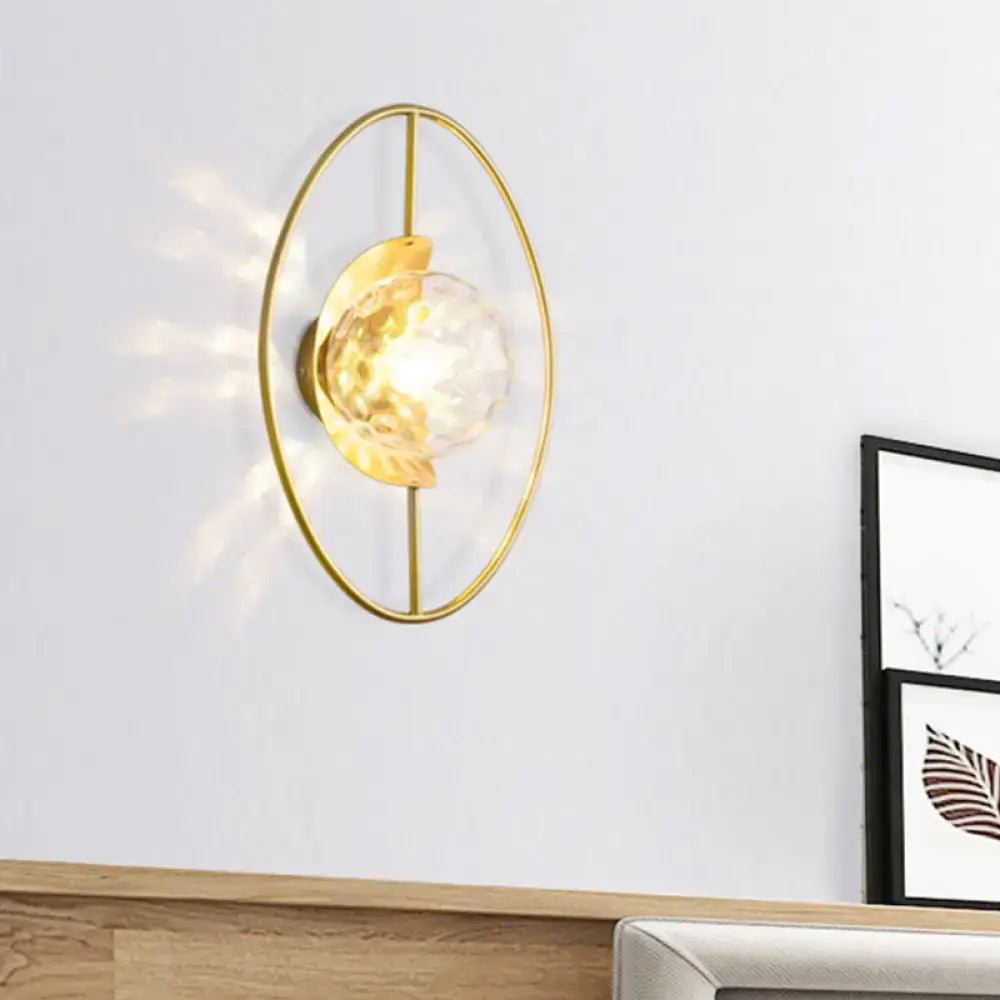 Gold-toned oval wall lamp fixture with faceted white glass globe and black leaf-shaped accent for bedroom use