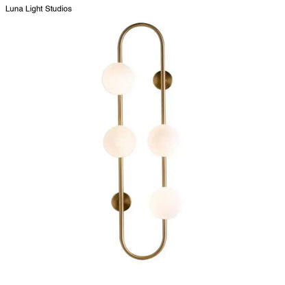 Modern black and gold globe wall sconce with brass finish and white glass globe shades for bedroom lighting