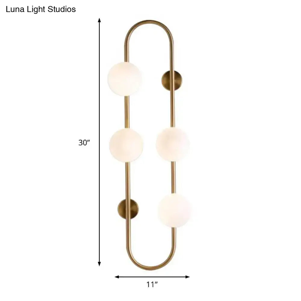 Brass-finished wall sconce with four frosted white glass globe shades in a modern curved globe wall sconce design
