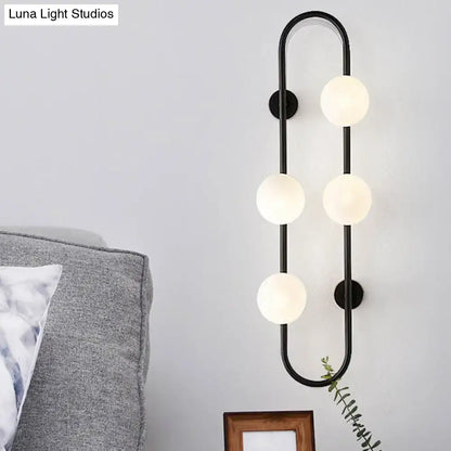 Modern black metal wall sconce with five white glass globe bulbs in a curved vertical design for bedroom lighting