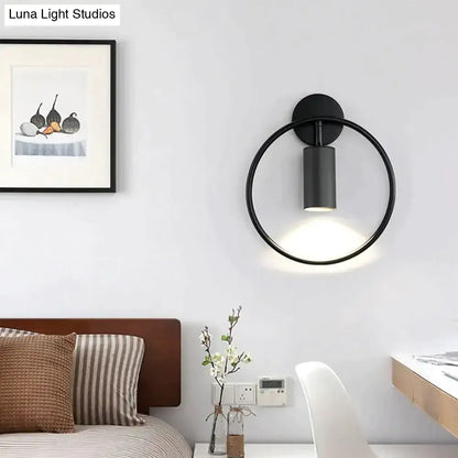 Modern black and gold irwin wall lamp with a black circular wall sconce and cylindrical light fixture for bedroom use