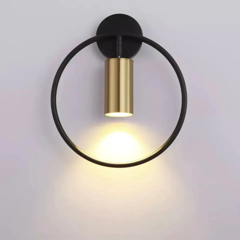 Modern black and gold irwin wall lamp with brass cylindrical light fixture emitting warm illumination for bedroom sconce