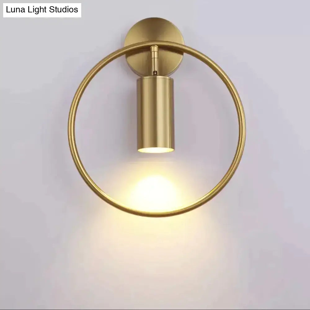 Modern black and gold irwin wall lamp featuring a gold-finished circular ring and cylindrical light fixture wall sconce
