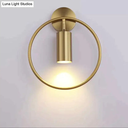 Modern black and gold irwin wall lamp featuring a gold-finished circular ring and cylindrical light fixture wall sconce