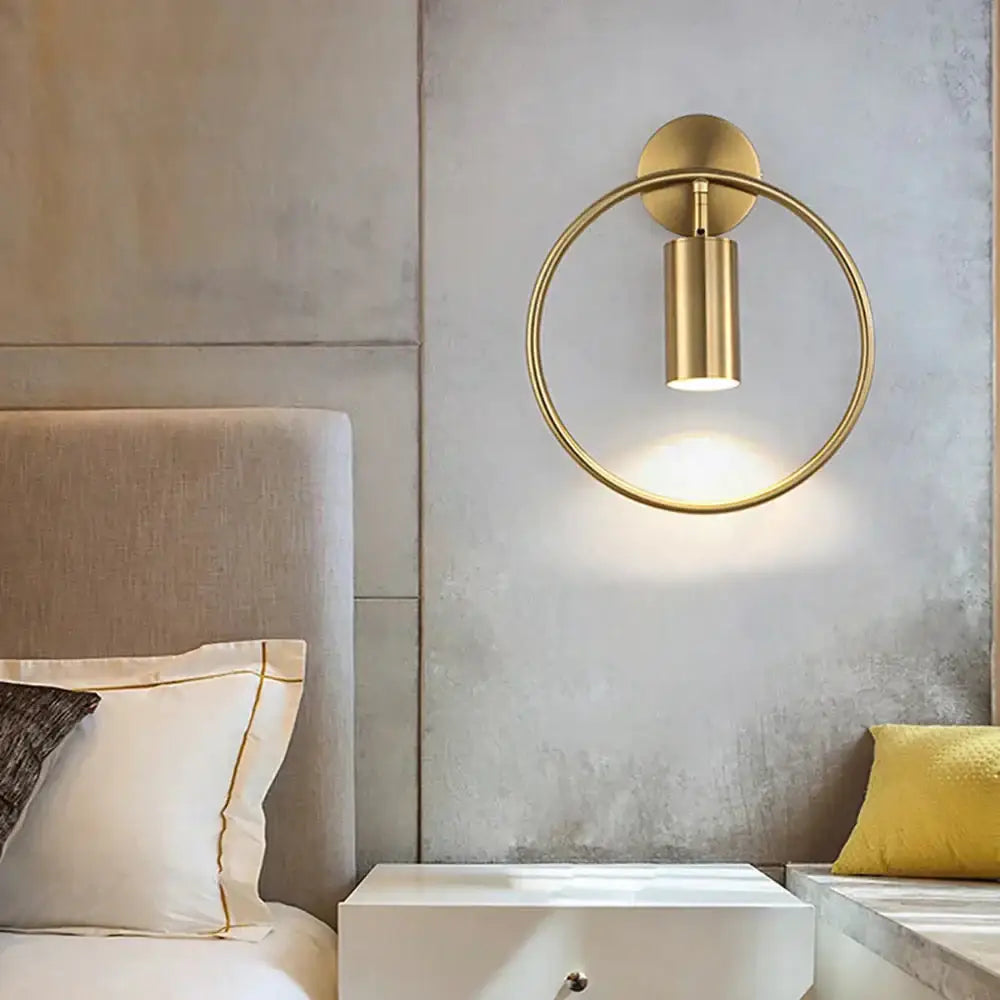Modern black and gold irwin wall lamp features a gold-toned circular wall sconce with a cylindrical light fixture