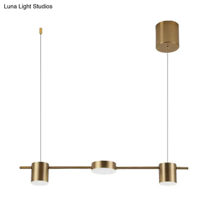 Modern black gold ceiling light fixture with brass finish, three cylindrical shades, and frosted glass diffuser for kitchen island