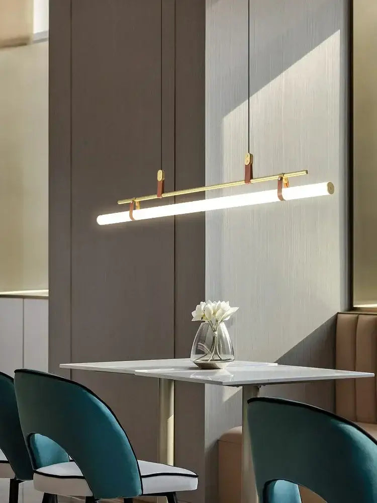 Modern black gold leather tube led pendant light with gold leather accents hanging above dining table