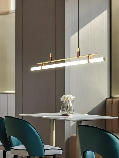 Modern black gold leather tube led pendant light with gold leather accents hanging above dining table