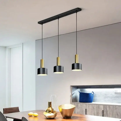 Modern black and gold metal finish pendant light with cylindrical shades and brushed nickel accents for kitchen use