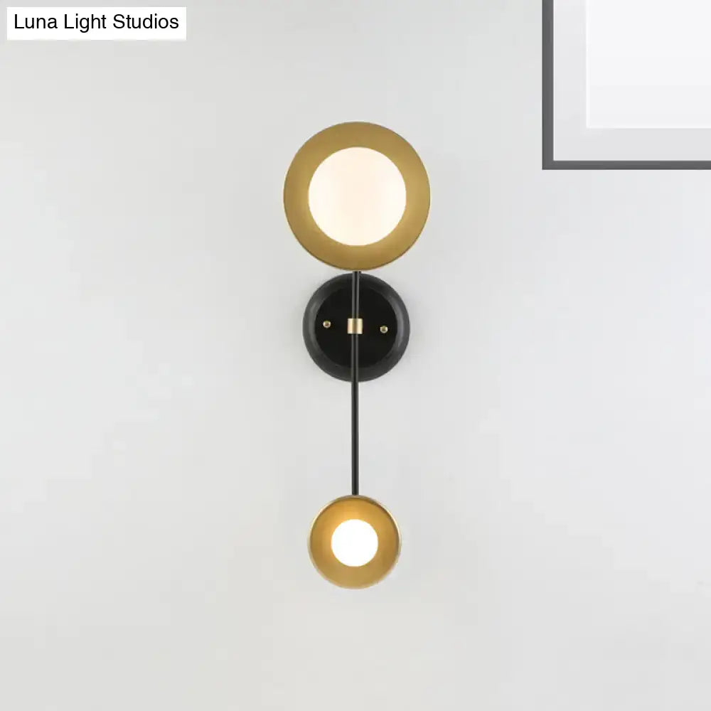 Modern black and gold wall sconce with milky glass circular shades and black mounting base for bedroom reading