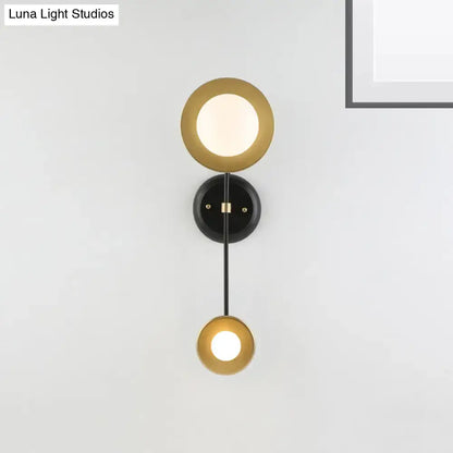 Modern black and gold wall sconce with milky glass circular shades and black mounting base for bedroom reading