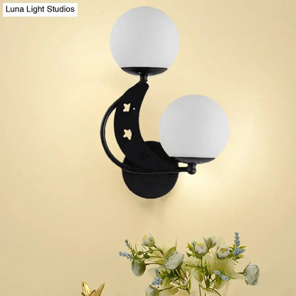 Modern black wall lamp featuring a crescent moon shape with milky glass ball shades and cut-out star details for bedroom use