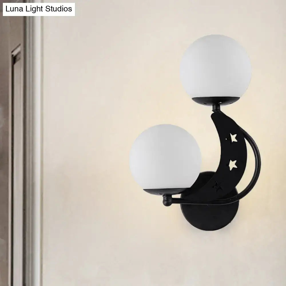 Modern black metal wall lamp with crescent moon design and two frosted milky glass ball shades for bedroom use