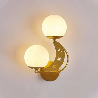 Gold-toned crescent moon wall lamp with milky glass ball shades and star cutouts for modern bedroom lighting