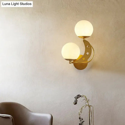 Gold-toned crescent moon wall lamp with milky glass ball shades and star cutouts for bedroom lighting
