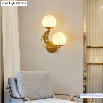 Gold-toned crescent moon wall lamp with star cutouts and two frosted milky glass ball shades for bedroom lighting