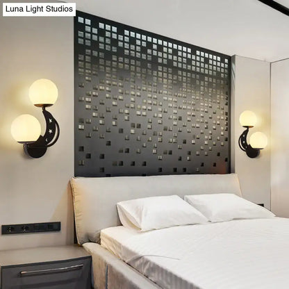 Modern black and gold wall lamp with moon and star motifs featuring milky glass ball shades for bedroom lighting