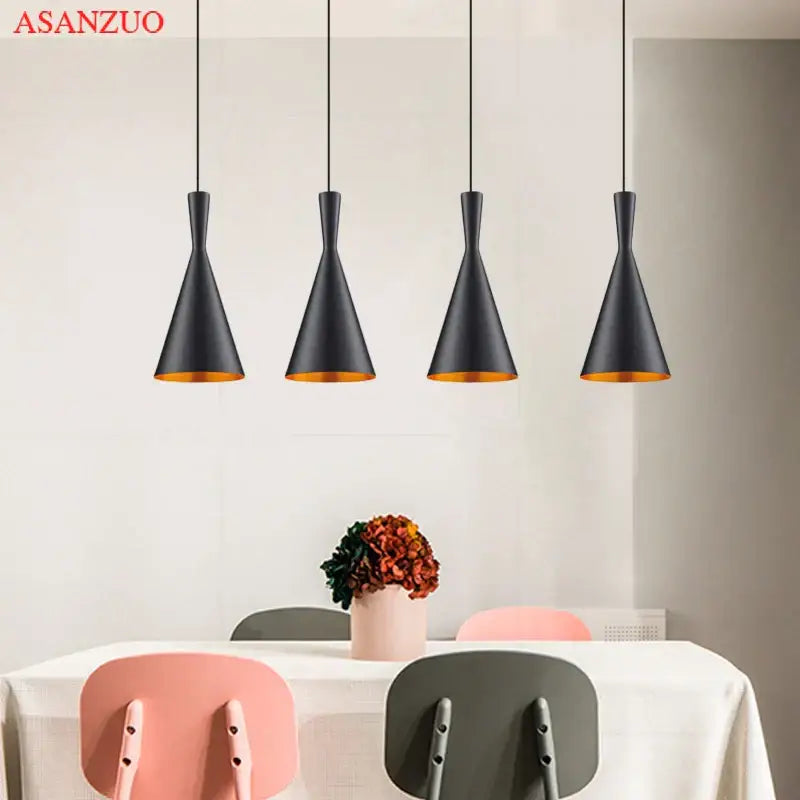 Four sleek black pendant lights with gold-lined interiors form a modern gold musical pendant light for dining room