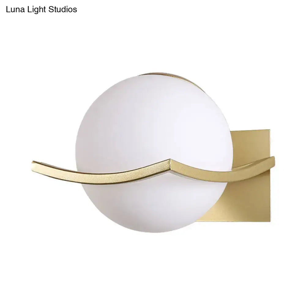 A modern black and gold opal glass globe wall sconce with frosted white shade and gold-toned metal arms for bedroom lighting