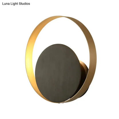 Modern black and gold metallic orbit sconce light with a gold-toned circular design and matte black central disc for living room ambient lighting